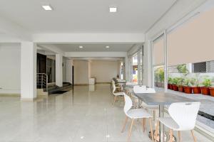 a dining room with white chairs and tables and windows at AVS Prime in kolkata +22 photos
