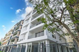a white apartment building with a tree in front of it at AVS Prime in kolkata