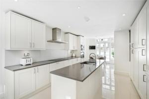 a white kitchen with white cabinets and a sink at 4 bedroom home by Buckingham Palace in London