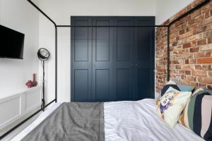 een slaapkamer met een blauwe deur en een bakstenen muur bij Retro Apartamenty in Przemyśl