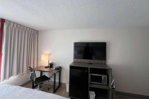 a hotel room with a bed and a television and a desk at Ramada by Wyndham Kingston in Kingston