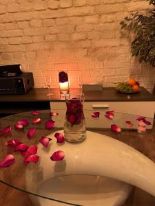 un tavolo di vetro con petali di rosa sopra con un vaso di Oasis-spa a Praga
