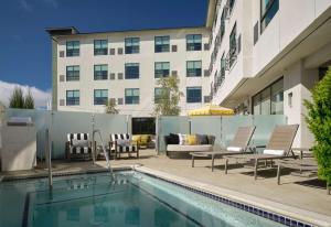 a pool with chairs and a couch next to a building at The Knoll Hotel Napa Valley, Tapestry Collection by Hilton in Napa