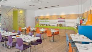 a restaurant with white tables and purple chairs at Hey Lou Hotel Hildesheim in Hildesheim