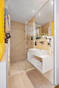 a bathroom with a white sink and a shower at Hey Lou Hotel Hildesheim in Hildesheim