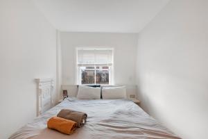 a white bedroom with a bed with an orange towel on it at LUXURY NEW 1 bed SUITE BOND ST APART’M MAYFAIR in London