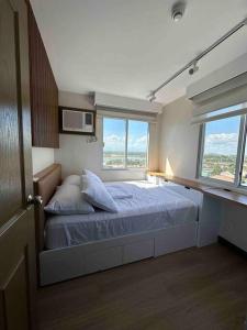 伊洛伊洛的住宿－Cozy 2 Bedroom End Unit，一间卧室配有带2个枕头的床和2个窗户。