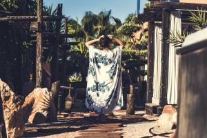 Une femme en robe blanche marchant dans une rue dans l'établissement Paradis Plage Surf Yoga & Spa, à Taghazout