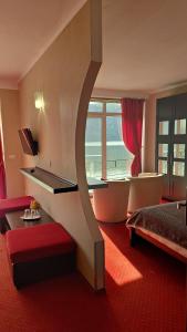 ドゥボバにあるPensiunea Decebal Resort - Cazanele Dunariiのベッドと大きな窓が備わるホテルルームです。