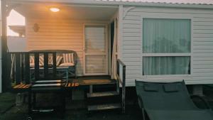 un porche de una casa con una silla y una ventana en Bungalow Mobilhome Agua en Chiclana de la Frontera, Cádiz, en Chiclana de la Frontera