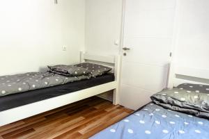 two beds in a room with white walls and wooden floors at ARIA DELUXE Mobile Homes with Terme Čatež Tickets in Čatež ob Savi