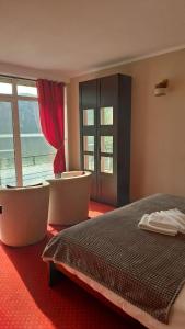 a bedroom with two chairs and a bed and a window at Pensiunea Decebal Resort - Cazanele Dunarii in Dubova