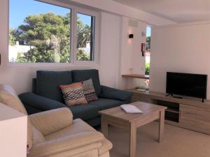 a living room with a blue couch and a tv at Nure Villas Mar y Mar in Cala en Blanes
