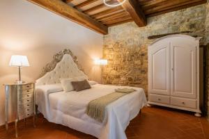 una camera con un letto bianco e un muro in pietra di Villa Le Polle di Meletro a Chianni
