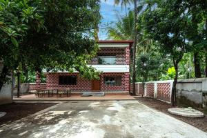 una casa de ladrillo rojo con un patio frente a ella en Beach Heaven Villa, Nandgaon en Murud
