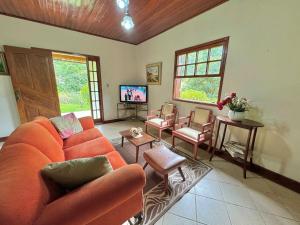 ein Wohnzimmer mit einem orangenen Sofa und Stühlen in der Unterkunft Casa de campo para relaxar in Nova Friburgo
