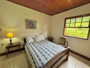 Schlafzimmer mit einem Bett und einem Fenster in der Unterkunft Casa de campo para relaxar in Nova Friburgo