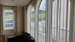 - un salon avec 2 grandes fenêtres et un canapé dans l'établissement 2 bedroom caravan near Llanberis, on the edge of Snowdonia, à Llanddeiniolen