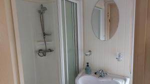 La salle de bains est pourvue d'un lavabo et d'un miroir. dans l'établissement 2 bedroom caravan near Llanberis, on the edge of Snowdonia, à Llanddeiniolen