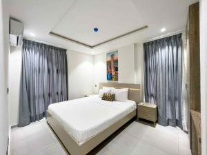 a bedroom with a large white bed and windows at Park Apartments in Accra