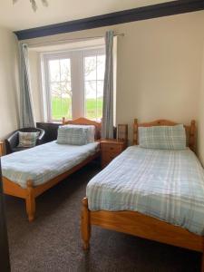 two beds in a room with a window at Kingarth Hotel in Kilchattan