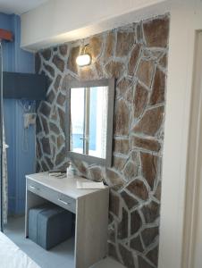 a stone wall in a bedroom with a desk and a mirror at Oceanida Bay Hotel in Pythagoreio