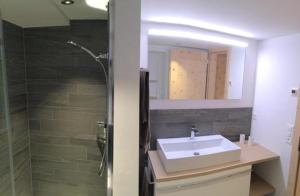 ein Bad mit einem Waschbecken, einer Dusche und einem Spiegel in der Unterkunft Chesa Kober, Wohnung 4 in Pontresina