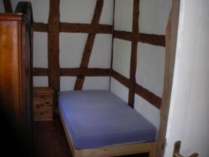 a small bed in a room with a wall at Tolles Ferienhaus in Presseck mit Grill und Garten in Presseck