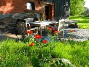 een patio met een tafel, stoelen en bloemen bij Ferienhaus in Klingenthal mit Garten und Terrasse in Klingenthal