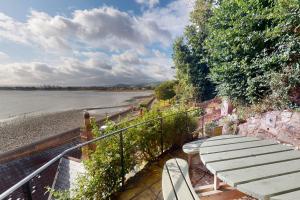 a wooden bench sitting next to a body of water at Captains Cottage Minehead in Minehead