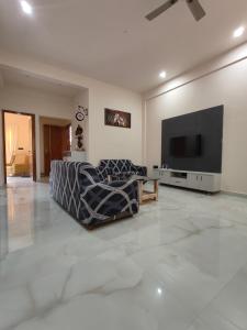 een woonkamer met een bank en een flatscreen-tv bij 2 Bedroom Apartment near Vijayanagar, Bangalore in Bangalore