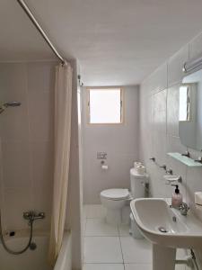 a white bathroom with a toilet and a sink at TERPSICHORE Holiday Apts in Limassol