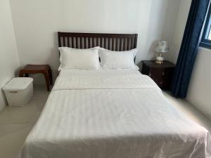 Schlafzimmer mit einem weißen Bett mit einem Kopfteil aus Holz in der Unterkunft Dreamy Sunset Bay in Manila