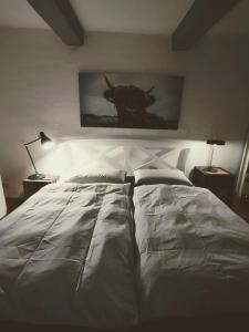 a white bed in a bedroom with a picture of a bull at Eulenhof1843 in Poppenbüll