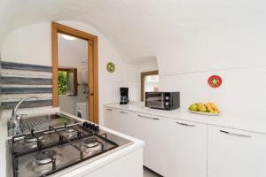 a white kitchen with a stove and a sink at Casa Anna Nerano in Nerano +11 photos