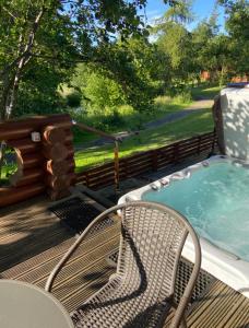 a deck with a chair and a hot tub at Laura's Lodge Hot Tub Log Cabin, Felmoor Park, Morpeth, Northumberland in Felton