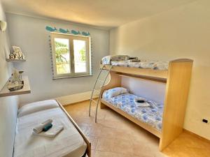 a room with three bunk beds and a window at Villa Cice Stintino in Stintino