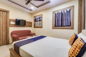 een slaapkamer met een bed, een stoel en een televisie bij OYO Flagship Horas Regency in Rānchī