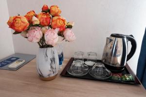 eine Vase mit Blumen auf einem Tisch neben einer Kaffeemaschine in der Unterkunft Asia Hotel in Bischkek