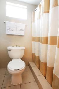 een badkamer met een toilet en een douchegordijn bij Hotel Boulevard Mexicali in Mexicali