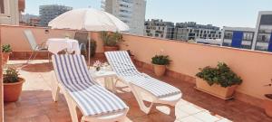 - un balcon avec une table, des chaises et un parasol dans l'établissement Cozy and sunny penthouse Fira BCN, à L'Hospitalet de Llobregat