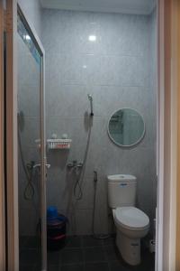 ein Bad mit einer Dusche, einem WC und einem Spiegel in der Unterkunft Cipada Guesthouse syariah in Sumedang