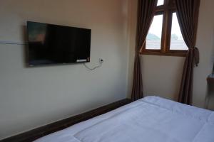 a bedroom with a bed with a flat screen tv on the wall at Cipada Guesthouse syariah in Sumedang
