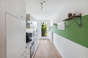 a kitchen with white cabinets and green accent wall at Sali-Homes Boarding Haus Monteur-Wohnungen Balkon Vollküche Autobahnähe in Markranstädt