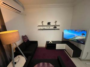 a living room with a black couch and a flat screen tv at Location Location Location in Sliema