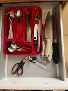 a red tray filled with utensils in a drawer at Location Location Location in Sliema