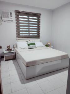 a white bedroom with a large bed and a window at Sunrise Beach Residences u2 in Olongapo