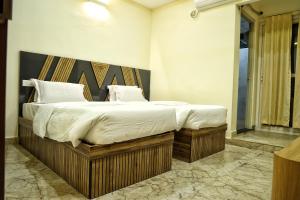 een slaapkamer met een groot bed met witte lakens en kussens bij Hotel Aaryan Comforts - Peenya in Bangalore