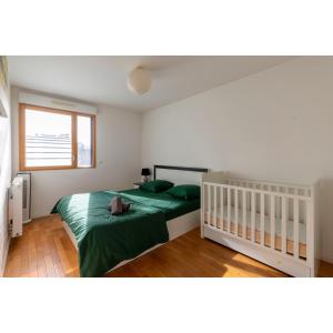Un dormitorio con una cama verde y una ventana en "Spacieux et lumineux" proche Paris, parking gratuit, en Cachan