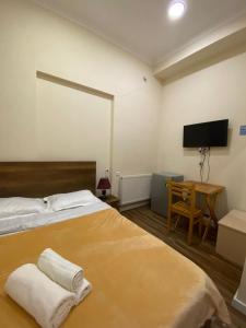 a bedroom with a bed and a desk and a television at Balcony Hotel in Tbilisi City